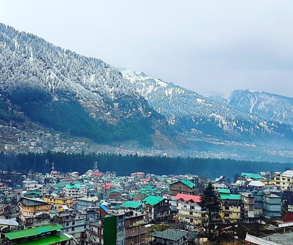 Mountain town with snowy peaks and colorful buildings.