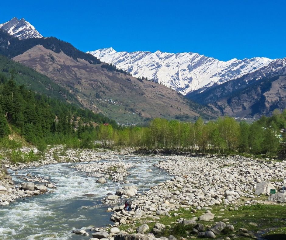 A picturesque river traverses a vibrant valley, surrounded by impressive mountains that enhance the scenic landscape