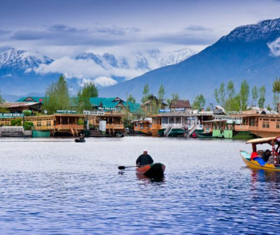 People navigate small boats on serene waters, surrounded by breathtaking mountains, capturing a moment of natural beauty.